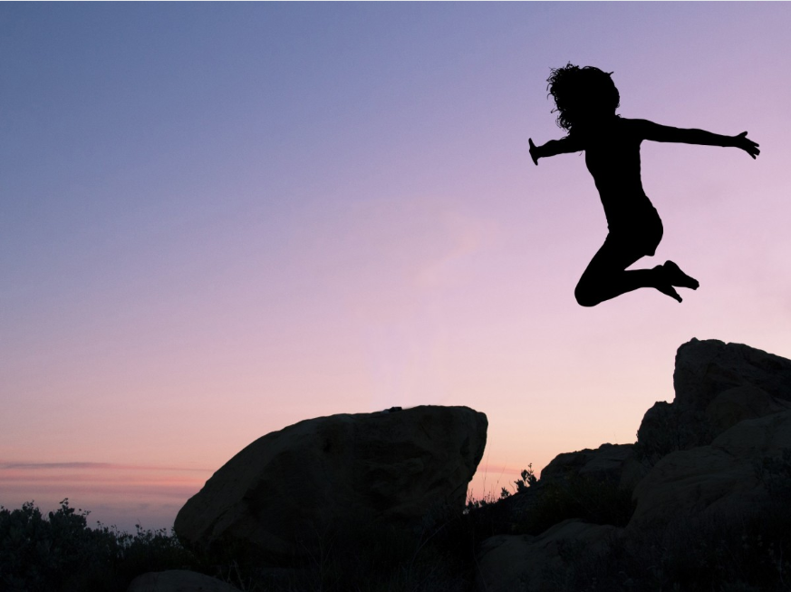 girl jumping from rock in a purple sunset